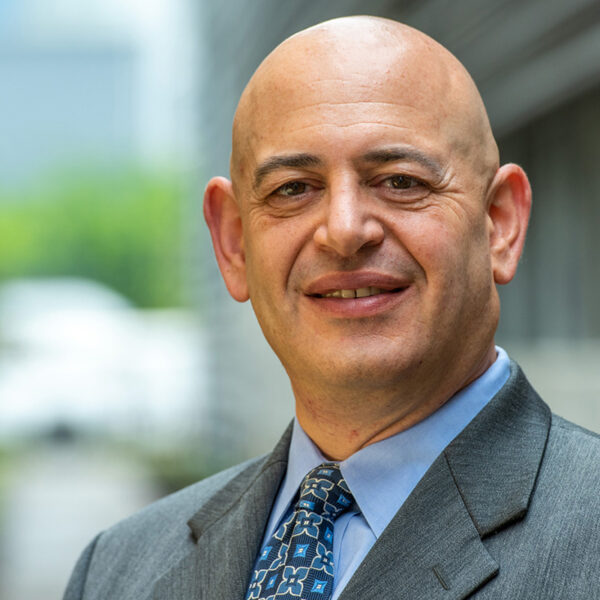 Portrait of Nat Mund smiling in a gray suit with a blue floral patterned tie.