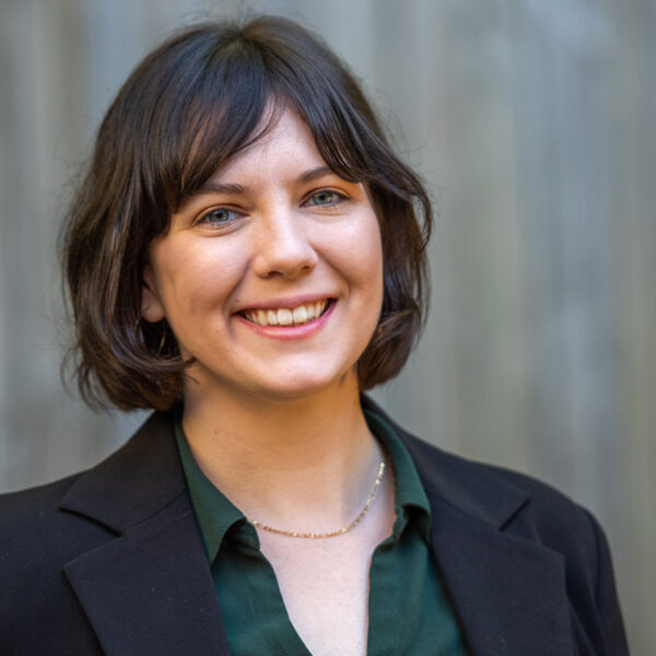 Portrait of Alyssa Prater smiling in a green top, black blazer, and thin gold chain necklace.
