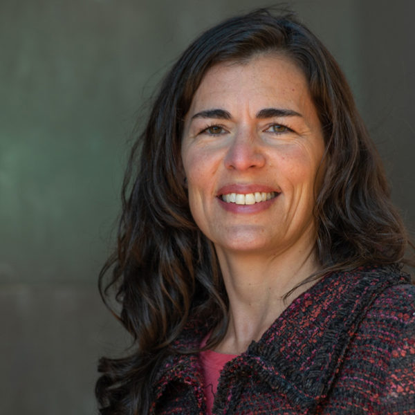 Portrait of Darah Palmer smiling in a multicolored blazer.