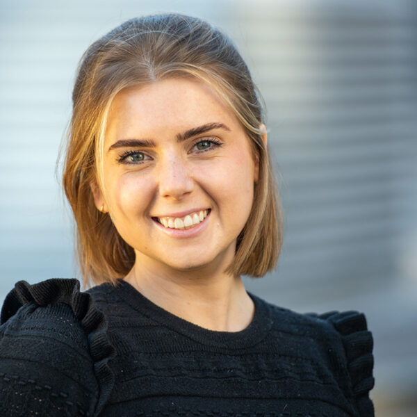 Portrait of Allie Swanson smiling in a black frocked sweater.